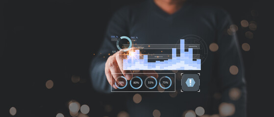 A person in dark clothing interacts with a glowing digital dashboard displaying blue bar graphs, pie charts, and percentages, symbolizing data analysis, performance tracking,and business intelligence.