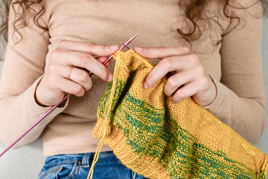 knitted pattern in woman hands. Girl holding knitting needles and beautiful knitting pattern. Woman with knitted pattern. Knitting hobby. Needlework background. 