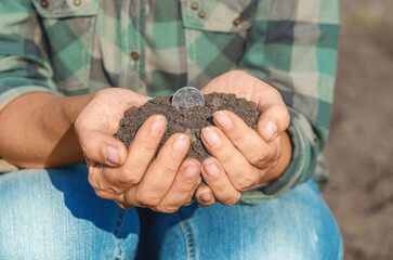 Female palms with soil with silver coin. Front view. Green business, ecology. Investing in land.