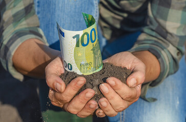 Farmer's palms with soil with 100 euro banknote. Green business, ecology. Investing in agriculture.
