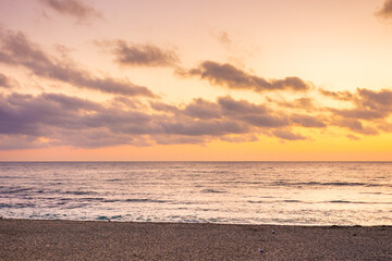 sea tide on the beach in summer. orange glow on the sky with clouds at dawn. beautiful nature condition before sunrise. dramatic weather at golden hour. zen velvet season vacation