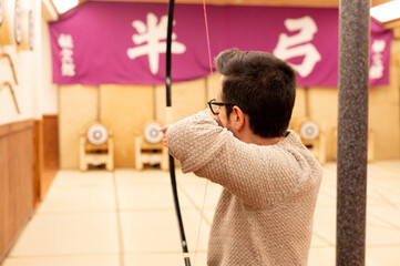 Man practicing traditional Japanese archery (Kyudo) indoors in Japan