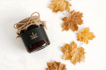 Natural botanical essence in a rustic jar with a leaf motif, surrounded by autumn leaves. Represents organic wellness and herbal preparation concepts.