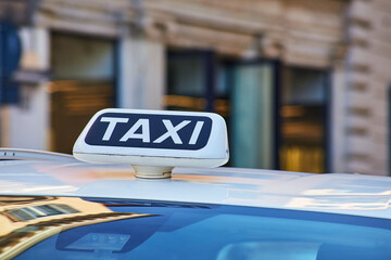 Italian Rome Taxi sign close-up view with the classic Roman street facade on the background