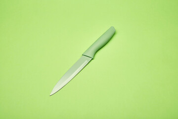 Bright green cooking chef's stylish modern design kitchen knife on the bright solid fond plain bright green background