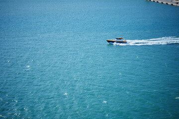 Small yellow pilot boat moving fast through blue harbor waters