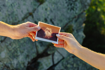 Couple holding ultrasound scan of their baby, pregnancy and parenthood concept