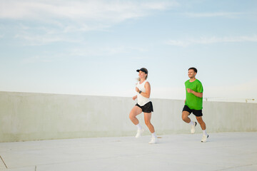 Joyful runners enjoying a fitness session on a sunny rooftop track