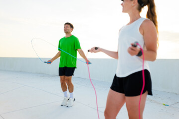 People jumping rope together on a rooftop in sunny weather