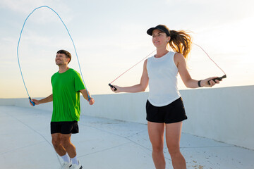 Jumping rope duo enjoys fitness challenge on a rooftop at sunset