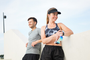 Couple enjoying post-workout relaxation at a coastal promenade