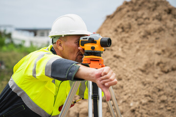 The survey team is using a theodolite and road construction plans. Civil engineers are measuring with surveying tools during the construction