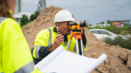 The survey team is using a theodolite and road construction plans. Civil engineers are measuring...