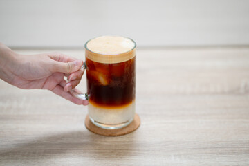 Close up and selective forcus hand holding glass of iced espresso in the morning.