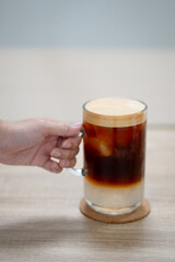 Close up and selective forcus hand holding glass of iced espresso in the morning.