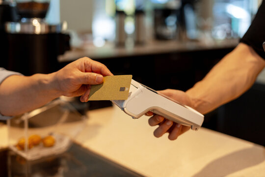Customer paying with credit card using pos terminal in cafe - Powered by Adobe