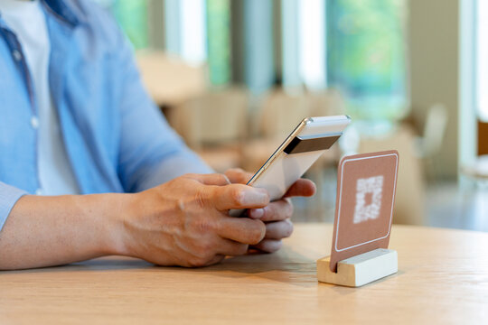 Customer scanning qr code with smartphone for online menu and ordering food in restaurant