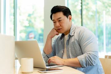 Asian Freelancer Working From Home Concentrating on Laptop