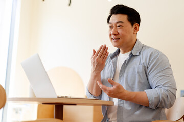 Asian businessman having video call on laptop and gesturing during online meeting