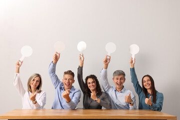 Panel of emotional judges voting with blank score signs at table against light grey background