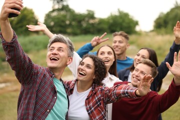 Team building. Group of happy people taking selfie outdoors