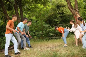 Team building. Group of happy people playing spider web game outdoors