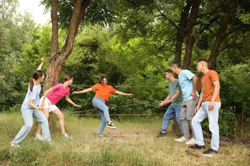 Team building. Group of happy people playing spider web game outdoors