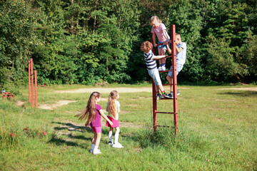 Obraz premium Children climbing ladder in nature on summer day