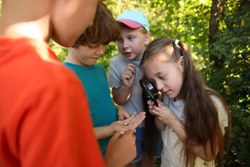 Children looking at snail through magnifying glass in nature © New Africa