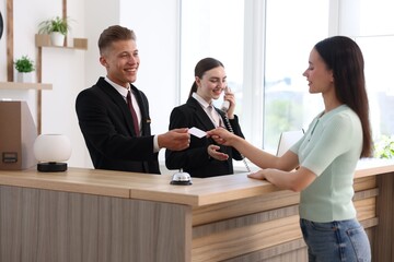 Smiling receptionists and client at reception desk in hotel