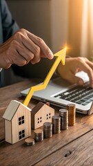 Real Estate Investment Growth; Hands Adjusting Upward Trending Arrow,  Laptop,  Wooden Homes, Coin Stacks.