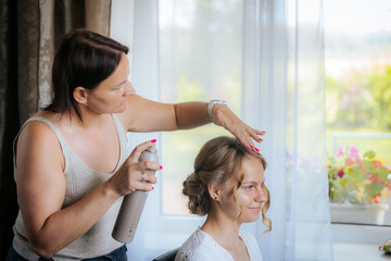 Close-up of a bride with closed eyes as a makeup artist applies eye shadow with a brush, capturing...