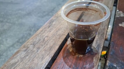 Intimate shot of a glass of hot black coffee placed on a wooden coaster on a wooden table. A...
