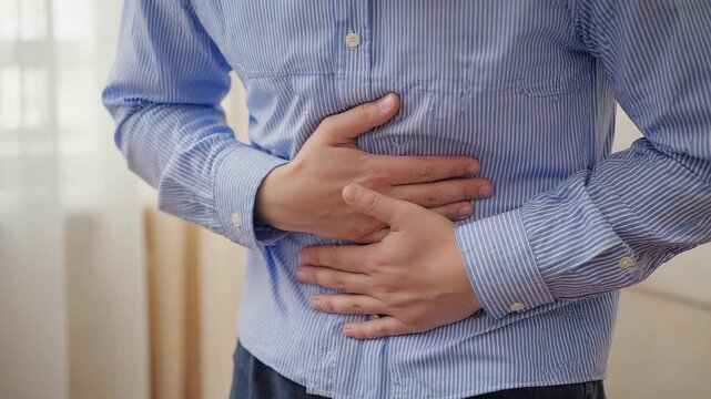 Man experiencing stomach discomfort in indoor setting during daytime