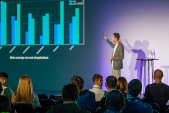 Speaker delivers presentation on research and business data to attentive audience during seminar.