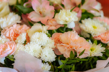 A delicate bouquet featuring pink carnations, white chrysanthemums, and soft greenery, wrapped in light pink paper. Ideal for weddings or celebrations.