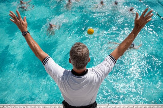 Water polo coach directing players in a vibrant swimming pool during an intense match