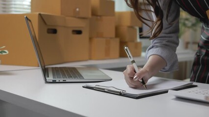 Woman working from home office, using laptop for online marketing, preparing product packages for customer delivery while managing small business startup operations - Powered by Adobe