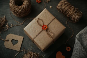 Handmade present wrapped with love. A rustic gift box decorated with natural twine, a small flower, and a heart tag.