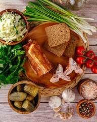 Sliced sausage with tomatoes and herbs on a wooden board.