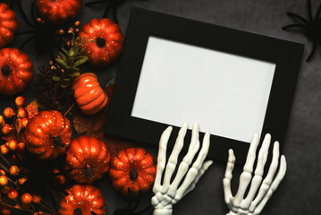 Top view of black frame with skeleton hand bones and Halloween pumpkins with space for text. Halloween concept background