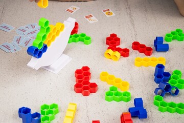 Colorful plastic building blocks scattered on a textured surface, with a game structure in the...