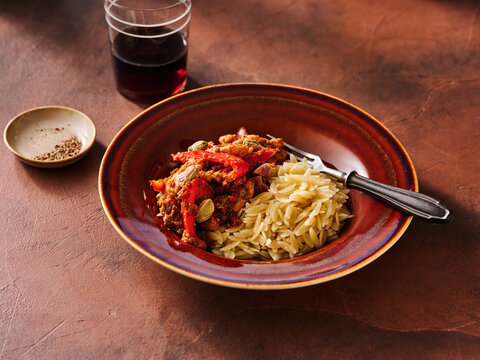 Savory sun dried tomato pesto wings are beautifully plated alongside a serving of orzo pasta, creating a vibrant and appetizing dish perfect for any meal time