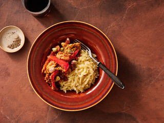 Delicious sun dried tomato pesto wings are served alongside fluffy orzo pasta, garnished with colorful peppers and nuts, ideal for a casual dinner or a festive meal with friends