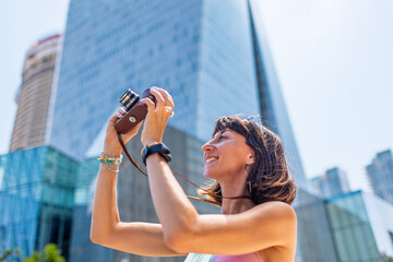 Stylish woman with a camera on the street. Portrait of a beautiful girl smiling on the street....