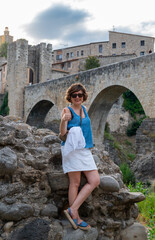 Tourist gesturing thumbs up in front of besalú medieval bridge in catalonia