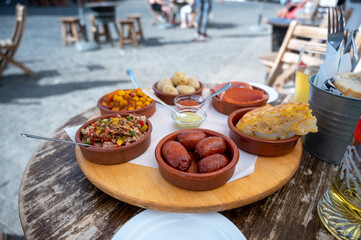 Spanish tapas selection featuring chorizo, patatas bravas, and tortilla española on a wooden board
