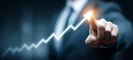 Businessman touching a glowing upward arrow graph symbolizing business growth, success, and financial progress

