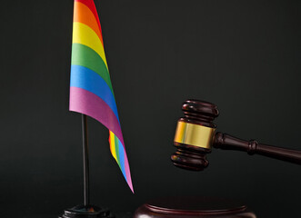 A rainbow flag stands proudly next to a gavel, representing the intersection of LGBTQ rights and...