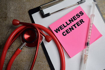 Concept of Wellness Center write on sticky notes isolated on Wooden Table. healthcare and...